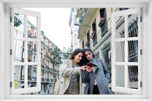 Two women using their smartphones in the street.