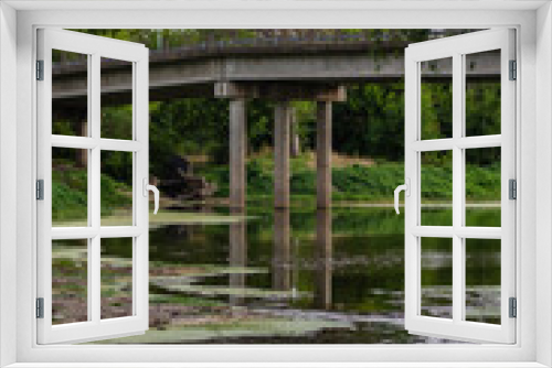 Fototapeta Naklejka Na Ścianę Okno 3D - tres columnas debajo de un puente reflejadas en agua contaminada