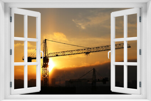 Fototapeta Naklejka Na Ścianę Okno 3D - Silhouette of construction crane and unfinished residential building on sunrise background. Housing construction, apartment block in winter city