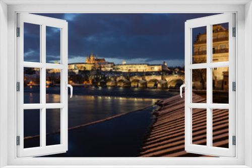Fototapeta Naklejka Na Ścianę Okno 3D - 
view of the snow-covered Prague castle St. Vitus Cathedral and Charles Bridge and on the shore of a wooden barrier at sunset in winter