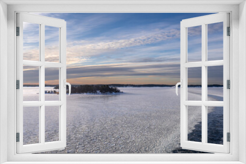 Fototapeta Naklejka Na Ścianę Okno 3D - Winter sunset. Beautiful view of the northern snow covered Baltic sea at sunset time in winter. Amazing sky bright colors and clouds on the horizon. Long trail of the cruise ship remains on the water.