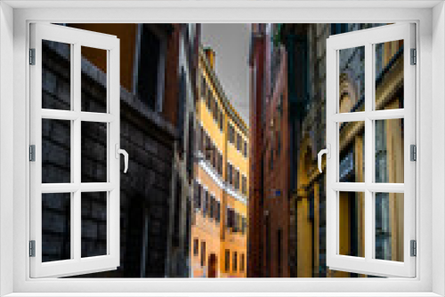 Fototapeta Naklejka Na Ścianę Okno 3D - Una estrecha y sombría calle de Roma con un edificio iluminado al fondo y con sus tradicionales colores anaranjados en tonos pastel