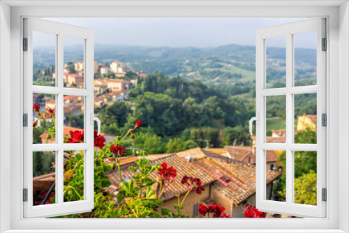 Fototapeta Naklejka Na Ścianę Okno 3D - Chiusi, Italy roof tiles view with historic old medieval buildings of town village in summer with foreground framing of red geranium flowers