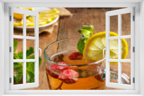 Fototapeta Naklejka Na Ścianę Okno 3D - green tea in a glass cup with strawberries mint and lemon on a wooden table and a teapot and lemon in a plate and mint leaves.