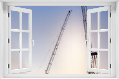 Fototapeta Naklejka Na Ścianę Okno 3D - Huge crane and construction plant.Tower Crane in Construction site. Industrial construction cranes and building silhouettes over sun at sunrise.Construction crane and skyscraper at sunset