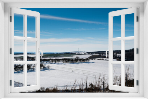Fototapeta Naklejka Na Ścianę Okno 3D - A scenic shot of a snowy landscape surrounded by trees with a blue clear sky