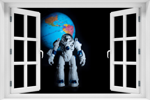Fototapeta Naklejka Na Ścianę Okno 3D - Toy astronaut on the background of the planet earth of the continents of America on a dark background like in space.