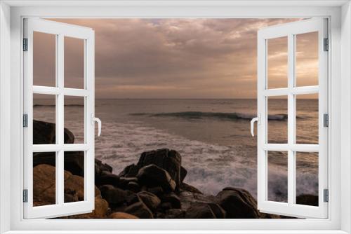 Fototapeta Naklejka Na Ścianę Okno 3D - Skaliste wybrzeże na tle wzburzonego oceanu z falami i zachodzącego słońca.