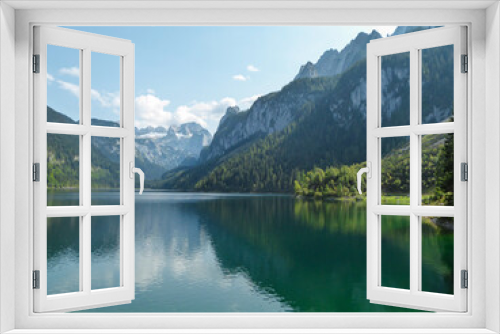 Fototapeta Naklejka Na Ścianę Okno 3D - Panoramic view on Gosau lake, with Dachstein glacier in the back in Austrian Alps. The lake is surrounded by high mountains, overgrown with tall trees. Sun reflects on the surface. Serenity  and calm