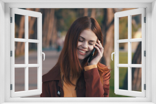 pretty woman in a coat With a phone in hand walking in the park rest