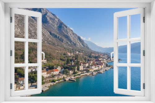 Fototapeta Naklejka Na Ścianę Okno 3D - Aerial shot of the old coastal town of Perast at the foot of the mountain. Seaside promenade, residential buildings with traditional balkan red roofs, ancient Cathedral and coastline