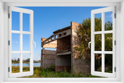 Fototapeta Naklejka Na Ścianę Okno 3D - Abandoned panel building. Industrial building is abandoned. It is overgrown with grass and trees. Concept - abandoned building of a decayed factory. He is missing windows and part of walls