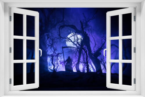 Fototapeta Naklejka Na Ścianę Okno 3D - Death with a scythe in the dark misty forest. Woman horror ghost holding reaper in forest, halloween concept