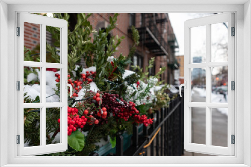 Fototapeta Naklejka Na Ścianę Okno 3D - Outdoor Christmas Holiday Pine Branches and Pine Cones with Red Berry and Light Decorations Covered with Snow Outside a Residential Building in New York City along a Sidewalk