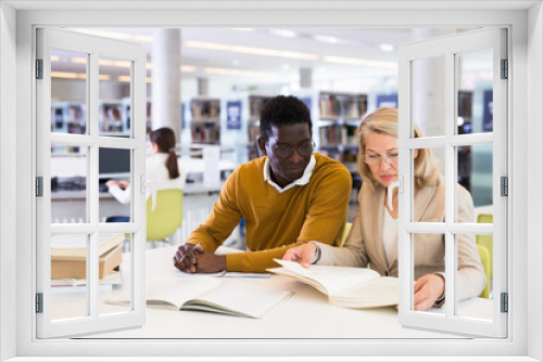 Two adult students studying together in public library. High quality photo