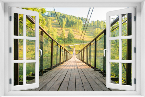 Fototapeta Naklejka Na Ścianę Okno 3D - Hanging wooden bridge. Suspension bridge, bridge  against the background of a green meadow and hills.