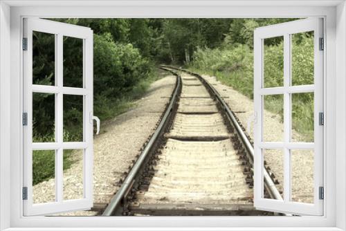 Fototapeta Naklejka Na Ścianę Okno 3D - turn of the railway. Steel rails on concrete sleepers disappear from view, going deep into the forest thicket