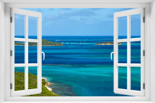 Fototapeta Naklejka Na Ścianę Okno 3D - View from hills on Mayreau: turquoise lagoon, lush green vegetation, coral reef and sailing  boats anchored in Tobago islands marine reserve.