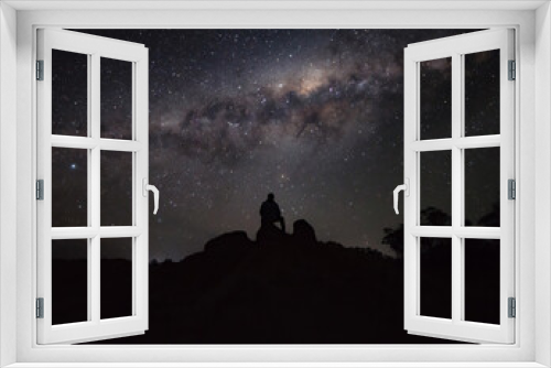 Fototapeta Naklejka Na Ścianę Okno 3D - Silhouette of a Person Sitting on a Rock Watching the Milky way