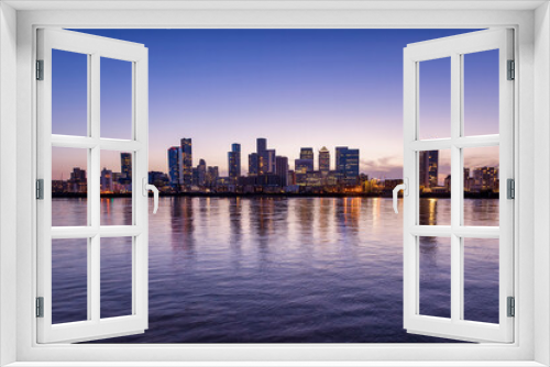 Fototapeta Naklejka Na Ścianę Okno 3D - Wide panoramic view over the Thames river to the new skyline of the financial district Canary Wharf in London, United Kingdom, during dusk