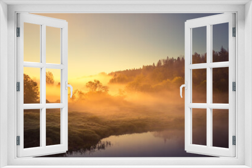 Fototapeta Naklejka Na Ścianę Okno 3D - A beautiful spring landscape of a river valley with morning mist. Springtime scenery of a river flowing through the forest. Water evaporating in sun rays. Springtime scenery of Northern Europe.