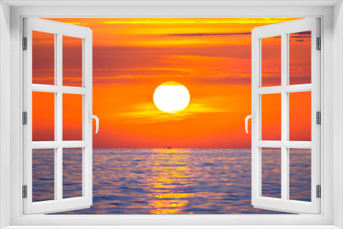 Fototapeta Naklejka Na Ścianę Okno 3D - Sun rising in the sea with a fishing boat in the rays of the sun above the waves. Beautiful sunrise on the ocean with a big and colorful sun in summer. A new day begins.