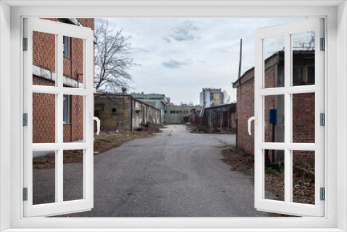 Fototapeta Naklejka Na Ścianę Okno 3D - Abandoned factories and warehouses in red brick, with broken windows and crumbling walls in Eastern Europe, in Pancevo, Serbia, former Yugoslavia, during a cold winter afternoon 