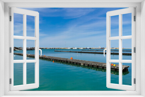 Fototapeta Naklejka Na Ścianę Okno 3D - Pontili di legno sul mare con boe e vista sul porto in una giornata di sole