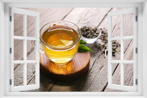 Fototapeta Naklejka Na Ścianę Okno 3D - Cup of green tea and dry leaves on wooden background
