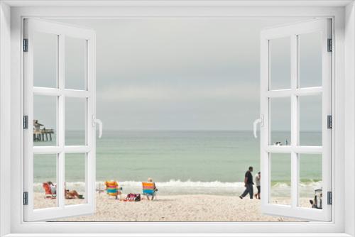 Fototapeta Naklejka Na Ścianę Okno 3D - front view, very far distance of people walking and sitting in beach chairs, at a tropical, sandy beach on a foggy morning, gulf of Mexico