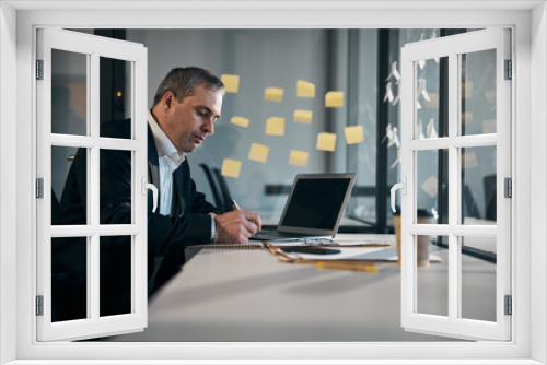 Serious businessman writing in notebook at work