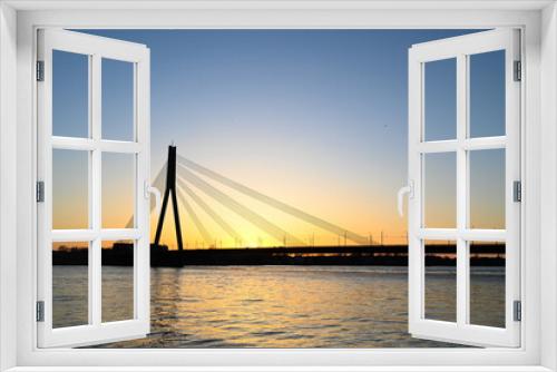 Fototapeta Naklejka Na Ścianę Okno 3D - Scenic view of long cable-stayed bridge silhouette over the river at sunset.