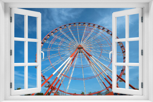 Fototapeta Naklejka Na Ścianę Okno 3D - A large red and white Ferris Wheel against a blue sky