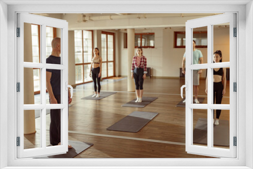 Teacher guides student in yoga class. Young sporty people practicing yoga in modern sport club