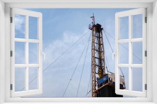 Fototapeta Naklejka Na Ścianę Okno 3D - Oil drilling rig derrick platform structure with blue sky background. Heavy industrial operation and energy business photo.