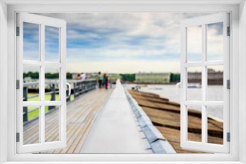 Fototapeta Naklejka Na Ścianę Okno 3D - Summer in the city, a walking terrace with panoramic views of the city and walking people. Close up view from the handrail on the sidewalk level