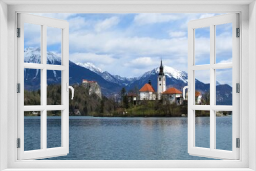 Fototapeta Naklejka Na Ścianę Okno 3D - View of the church on the island on lake Bled and Bled castle and snow covered peaks of Karavanke mountains with mountain Stol behind in Gorenjska, Slovenia