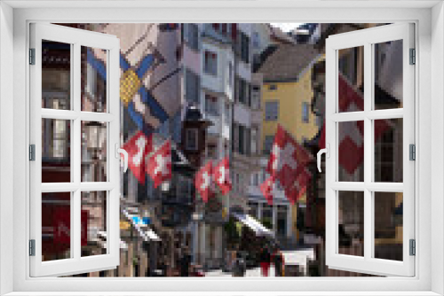 Fototapeta Naklejka Na Ścianę Okno 3D - Old medieval alley with beautiful oriels named Augustinergasse at the old town of Zurich with Swiss flags on both sides. Photo taken May 8th, 2021, Zurich, Switzerland.