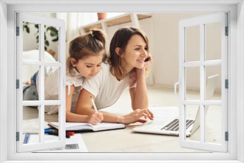 mom works at the computer while playing with her daughter