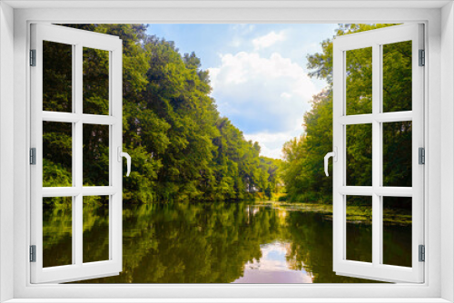 Fototapeta Naklejka Na Ścianę Okno 3D - Summer calm river sunny landscape. River surface with banks of densely overgrown green trees with the tops flooded with sunlight. Oskol river, Belgorod region, Russia.