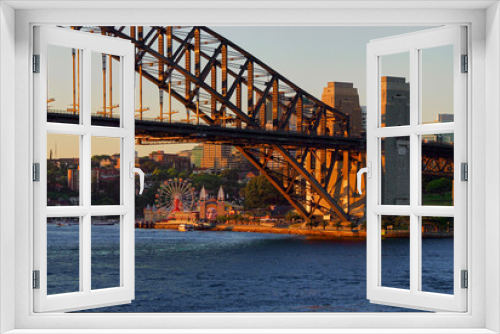 Fototapeta Naklejka Na Ścianę Okno 3D - The setting sun casts a warm glow on the Sydney Harbour bridge and cityscape at Darling Harbour in Sydney, Australia.