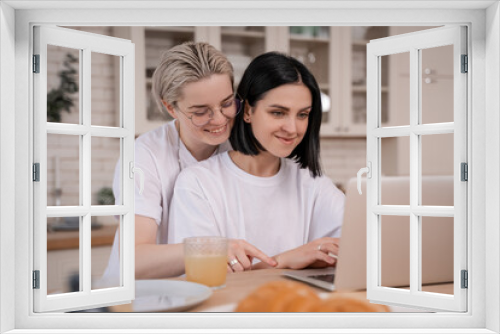 cheerful lesbian couple smiling while looking at laptop