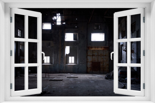 Fototapeta Naklejka Na Ścianę Okno 3D - Abandoned industrial backdrop. Old dark warehouse interior with concrete walls, rusty gate and light falling through broken windows
