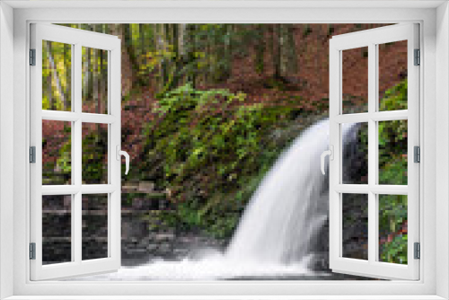 Fototapeta Naklejka Na Ścianę Okno 3D - Waterfall with a powerful stream of water, against the backdrop of a mountain slope with a green forest in Ukraine.