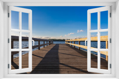 Fototapeta Naklejka Na Ścianę Okno 3D - Summer landscape with wooden jetty (pier) extend into the Nieuwe meer (New lake) is in southwest of Amsterdam, Beautiful blue sky with golden sunlight before the sunset, Amsterdamse Bos.