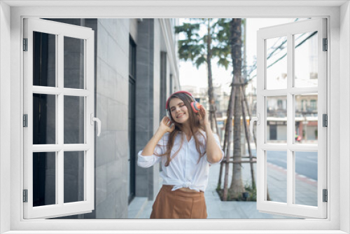 Young woman listening to music via headphones on the street. woman smiling happy using smartphone and headphones