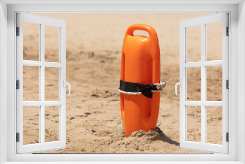 Fototapeta Naklejka Na Ścianę Okno 3D - An orange rescue buoy, tipped into the sand, ready to be used in any relief and rescue action, on the beach of Torrenostra, Castellon province, Valencian Community.