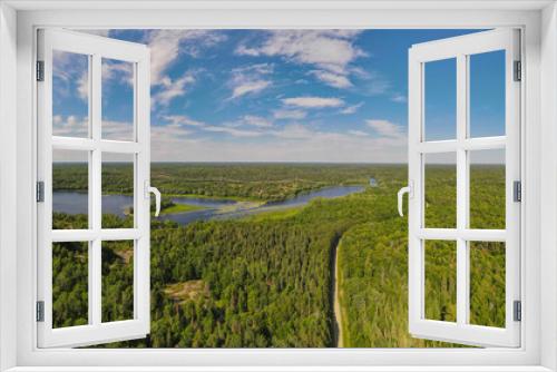 Fototapeta Naklejka Na Ścianę Okno 3D - Aerial bird's eye view drone panorama of green boreal coniferous forest, fresh water lakes and rivers and unpaved road winding trough the trees. Summer sunny day, blue sky. Northern Ontario, Canada.