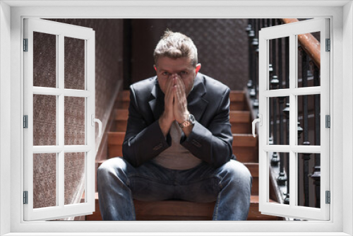 unemployment and divorce - dramatic lifestyle portrait of sad and depressed man on his 40s sitting indoors on staircase thoughtful and worried suffering depression problem