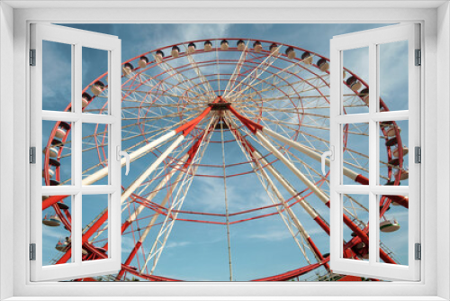 Fototapeta Naklejka Na Ścianę Okno 3D - A large red and white Ferris Wheel against a blue sky